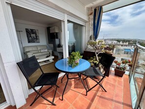 Ein Balkon mit Tisch und Stühlen, einer Couch und Blick auf die Stadt.