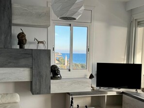 A modern living room with a large TV, a sculpture, and a view of the sea. - Luxury Penthouse with Panoramic Sea Views (Vilanova i la Geltru)
