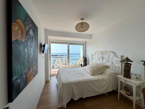 Ein Schlafzimmer mit einem Bett, einem Gemälde, einem Fernseher und Meerblick.