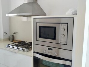 A kitchen with a built-in oven and microwave, a gas stove, and a stainless steel range hood. - Luxury Penthouse with Panoramic Sea Views (Vilanova i la Geltru)