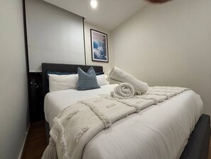Ett hotellrum med en snyggt bäddad säng, en sänggavel, en tavla som hänger på väggen och ett nattduksbord.
