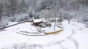 A snow-covered landscape with a wooden cabin surrounded by trees.
