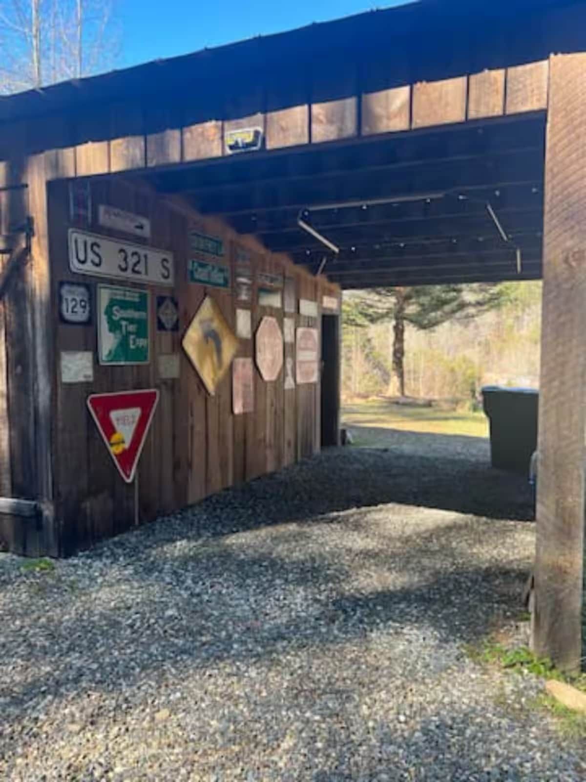 A wooden structure with various signs, including a US 321 S sign, a directional sign, and a yield sign.