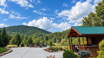 A lodge with a covered porch, a concrete patio, and a view of a forested mountain.