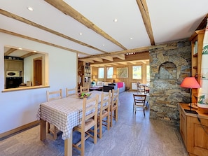 A dining area with a checkered tablecloth, wooden chairs, and a stone wall. - Chalet Mont-Blanc view - 6 guests (Combloux)