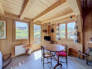 A wooden interior with a dining table, chairs, a television, and a view of the countryside. - Chalet Mont-Blanc view - 6 guests (Combloux)