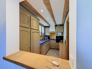 A kitchen with wooden cabinets, a countertop, and a microwave. - Chalet Mont-Blanc view - 6 guests (Combloux)
