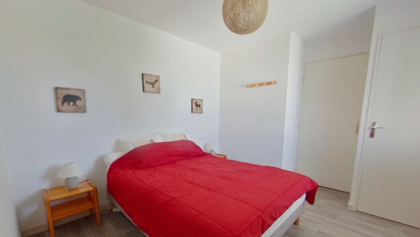 A bedroom with a bed, a nightstand, a lamp, and a door. - Apartment for 2 near Les Rousses center (Les Rousses)