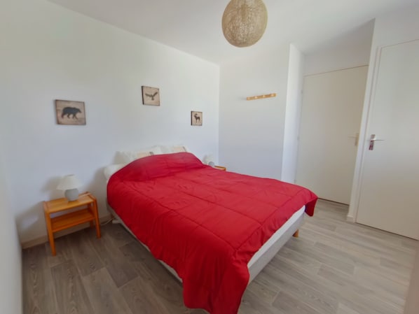 A bedroom with a bed, a nightstand, a lamp, and a door. - Apartment for 2 near Les Rousses center (Les Rousses)