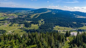 A mountainous landscape with a clear sky, dense forests, and a small settlement with visible roads and buildings. - Apartment for 2 near Les Rousses center (Les Rousses)