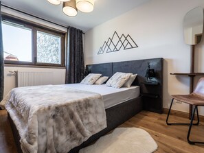 A bedroom with a bed, a nightstand, a chair, a window with curtains, and a wall art piece. - Spacious apartment with mountain view - 10 guests (La Plagne Montalbert)