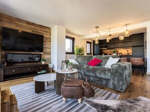 A modern living room with a large flat-screen TV, a sofa, a coffee table, and a unique animal-shaped ottoman. - Spacious apartment with mountain view - 10 guests (La Plagne Montalbert)
