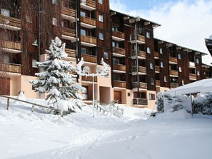 A multi-story building with balconies, surrounded by snow-covered trees and a snowy ground. - Apartment mountain view - 4 guests (Villarodin-Bourget)