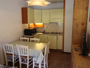 A compact kitchen with a dining table, chairs, a microwave, and a sink. - Apartment mountain view - 4 guests (Villarodin-Bourget)