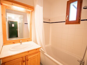 A bathroom with a wooden vanity, a sink, a mirror, and a bathtub. - Pleasant apartment pets welcome - 6 guests (Valfréjus)