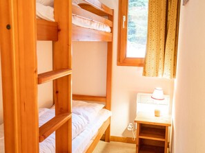 Een slaapkamer met stapelbed, bureau en raam.