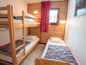 Ein Zimmer mit zwei Etagenbetten, Holzwänden, einem Fenster mit Vorhang und einer Wandleuchte.