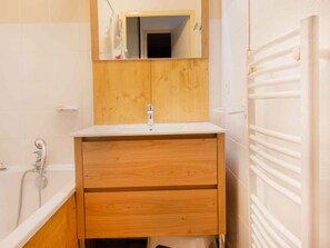Ein Badezimmer mit einem Holzbadezimmermöbel, einem weißen Waschbecken, einem Spiegel und einem weißen Handtuchhalter.