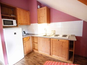 A compact kitchen with wooden cabinets, a white refrigerator, a microwave, a coffee maker, and a sink. - Spacious apartment, pets welcome - 8 guests (Valfréjus)