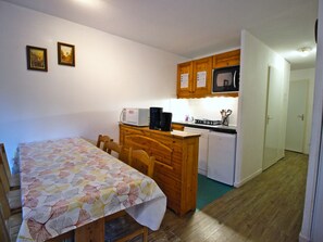 A compact kitchen with wooden cabinets, a microwave, and a small island with a coffee maker. - Apartment, piste view - 6 guests (Villarodin-Bourget)