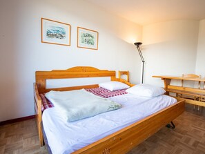 Ein ordentlich bezogenes Bett mit Holz-Kopfteil, einem Nachttisch und zwei gerahmten Bildern an der Wand.