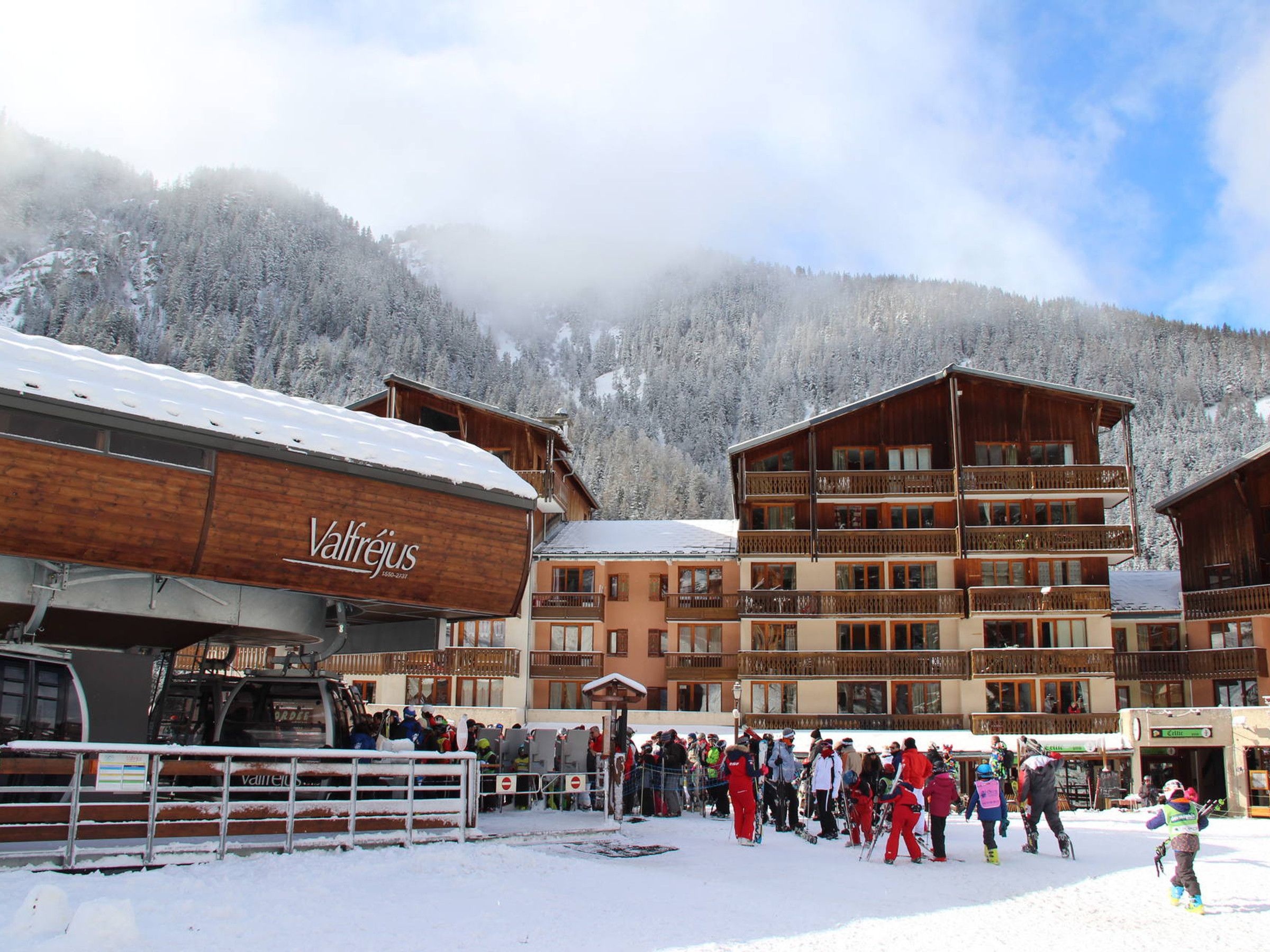 A ski resort with wooden buildings and a crowd of people.