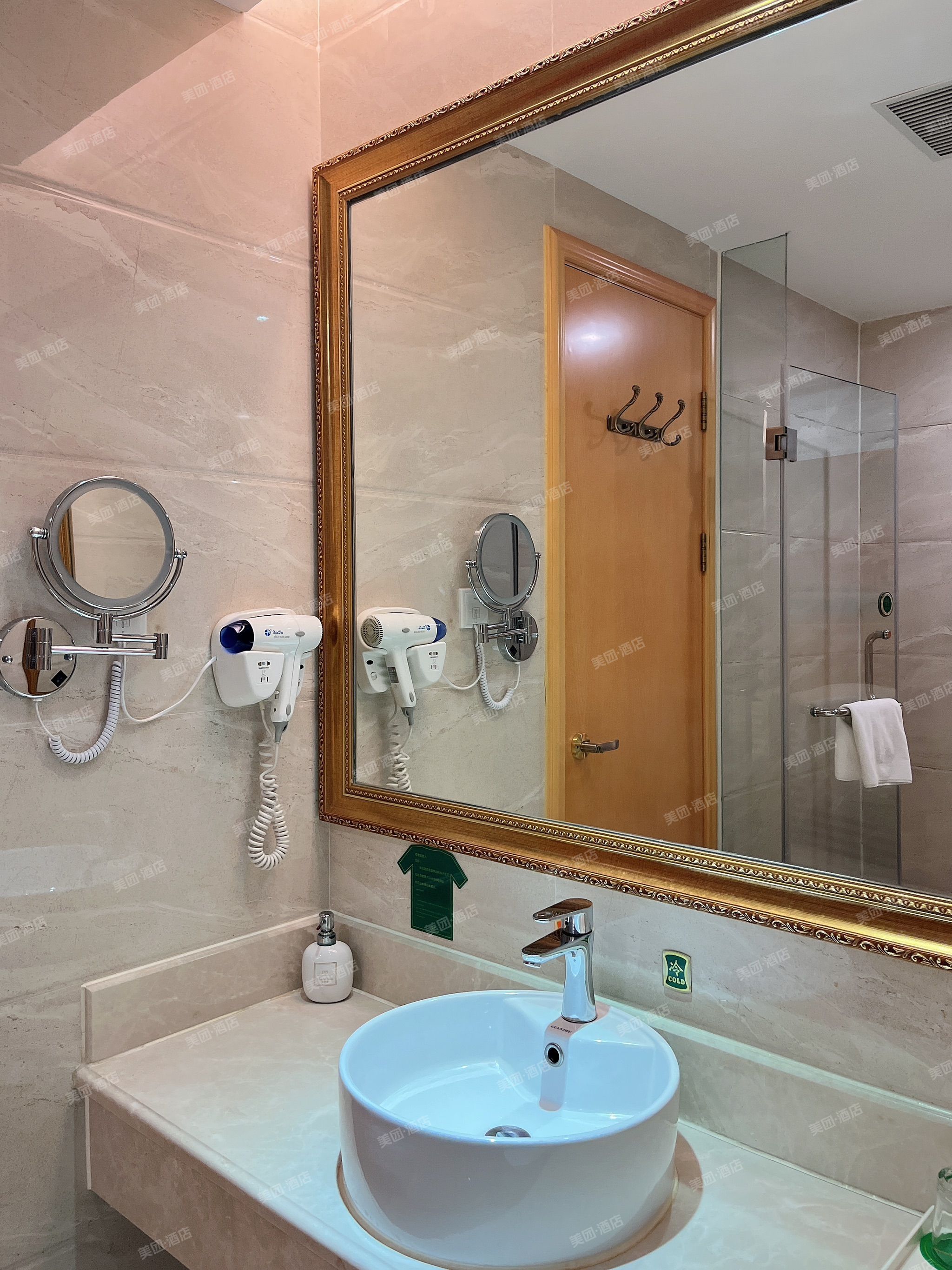 A bathroom with a large mirror, two hair dryers, a sink, and a shower.