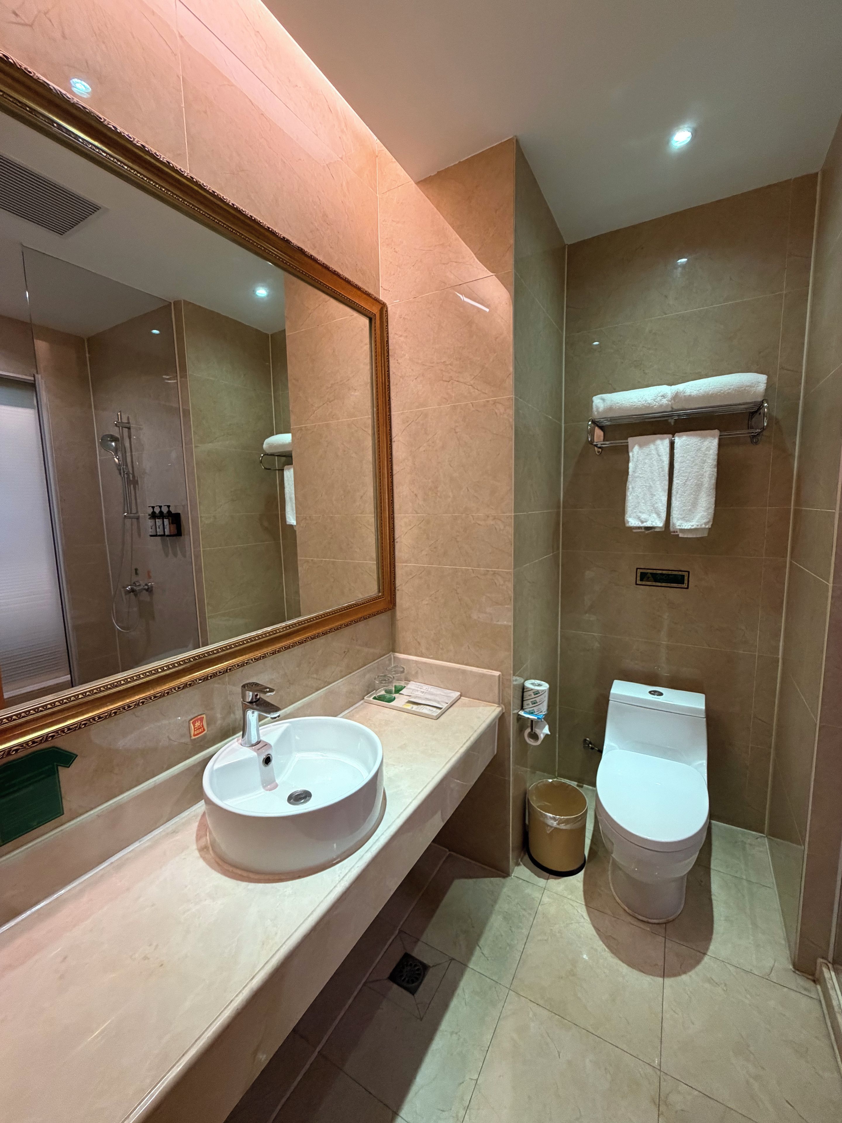 A modern bathroom with a large mirror, a sink, a toilet, and a shower area.