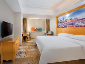 A hotel room with a bed, a desk with a flat-screen TV, a chair, a small table, and a window with curtains. - Vienna Hotel Shenzhen Universiade Center (Shenzhen)