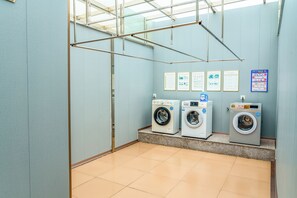 A laundry room with three washing machines, a metal drying rack, and informational posters on the wall. - Vienna Hotel Shenzhen Universiade Center (Shenzhen)