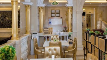 A hotel lobby with marble columns, a reception desk, and seating arrangements.