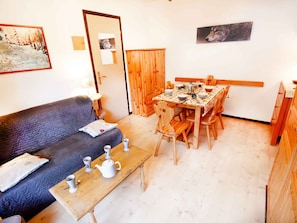 A cozy living room with a sofa, a dining table set for two, and a wooden cabinet. - Cozy apartment mountain view - 6 guests (Villarodin-Bourget)