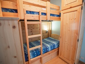 Ein Stockbett mit einer Leiter, ein Nachttisch und eine Wandleuchte.