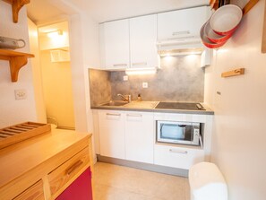 Eine kleine Küche mit weißen Schränken, einem eingebauten Backofen und einer Holz Arbeitsplatte.