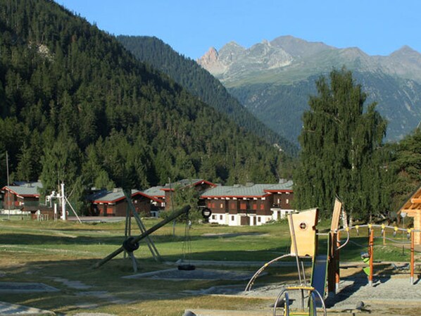 Eine gebirgige Landschaft mit Häusern, einer Schaukel und einem Spielplatz.