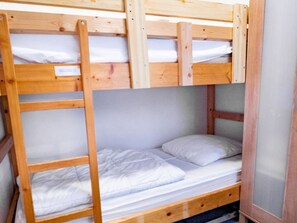 A bunk bed with a wooden frame and white bedding. - Apartment, pets welcome - 6 guests, mountain view (Villarodin-Bourget)