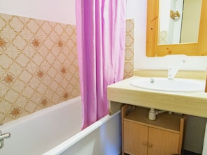 A bathroom with a bathtub, a sink, and a wooden cabinet. - Apartment, pets welcome - 6 guests, mountain view (Villarodin-Bourget)