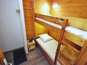 A bunk bed room with wooden walls and a small wooden stool. - Cozy and quiet studio - 4 guests (Villarodin-Bourget)