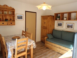 Ein gemütliches Zimmer mit einem Holztisch, Stühlen, einer Couch und einem Schrank mit Regalen.