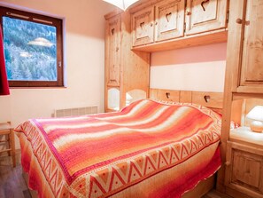 A room with a bed, wooden cabinets, a window with a view, and a heater. - Apartment mountain view - 6 guests (Villarodin-Bourget)