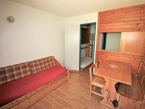 A compact room with a wooden bunk bed, a wooden table, and a plaid sofa. - Studio in village center, at the foot of slopes - 3 guests (Valfréjus)