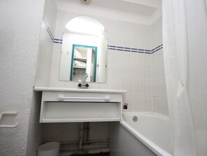 A bathroom with a white sink, mirror, and bathtub. - Studio in village center, at the foot of slopes - 3 guests (Valfréjus)