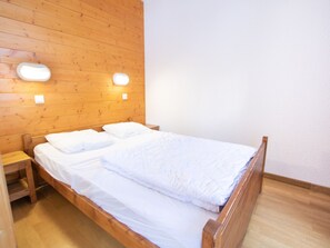 A single bed with white bedding in a room with wooden walls and a wooden floor. - Apartment mountain view - 4 guests (Villarodin-Bourget)