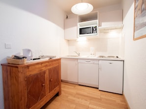 A compact kitchen with white cabinetry, a wooden cabinet, a microwave, a coffee maker, and a sink. - Apartment mountain view - 4 guests (Villarodin-Bourget)