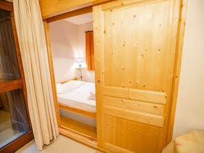 Una porta di legno che dà su una camera da letto con un letto, un comodino e una lampada.