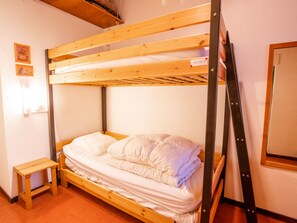 Een stapelbed met houten frame, een klein houten krukje en een witte matras.