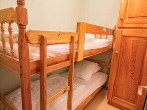 Kerrossänky, jossa on puiset päätyosat ja puinen vaatekaappi.