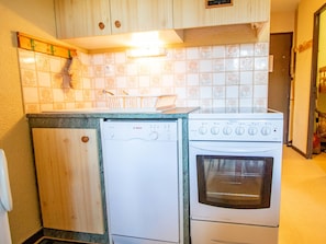 A compact kitchen with a dishwasher, oven, and a tiled backsplash. - Comfortable studio with balcony - 4 guests (Villarodin-Bourget)