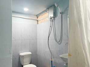 A bathroom with a toilet, a shower unit, and a sink. - Rock Sand Hostel (Koh Rong)