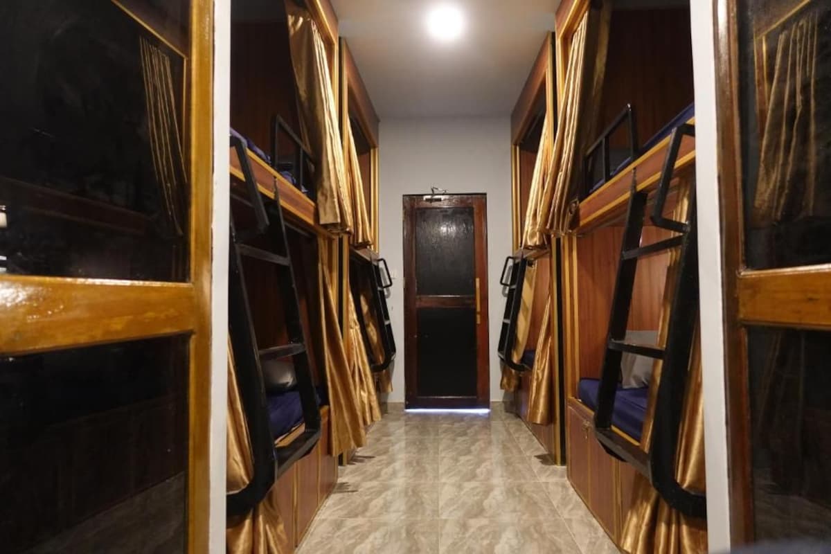 A corridor with bunk beds on either side, leading to a door at the end.